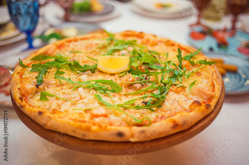 Pizza with cheese and arugula on a wooden board on the table closeup