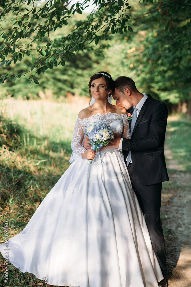 Dreamy wedding couple poses on the path in a green forest