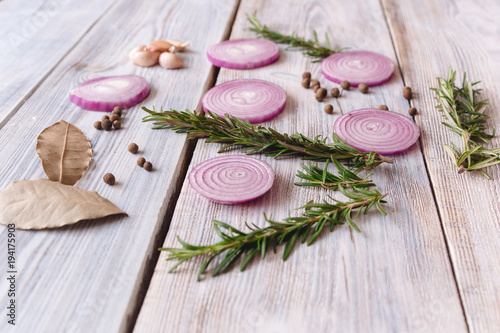 sliced onions and rosemary on white wooden background