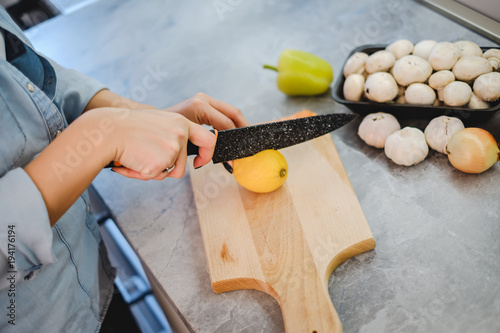 Female hand slicing lemon with knife