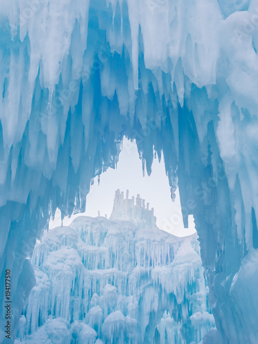 Fotografia Winter ice castle caves with frozen icicles at sunset.