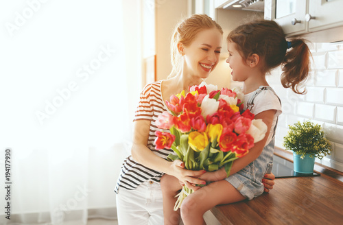 happy mother's day! child daughter   gives mother a bouquet of flowers to tulips.