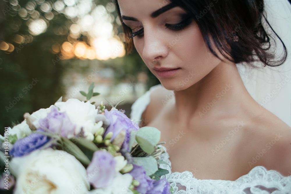 Stunning young bride stands in the forest with tall trees and morning sunshine Stunning young bride stands in the forest with tall trees and morning sunshine
