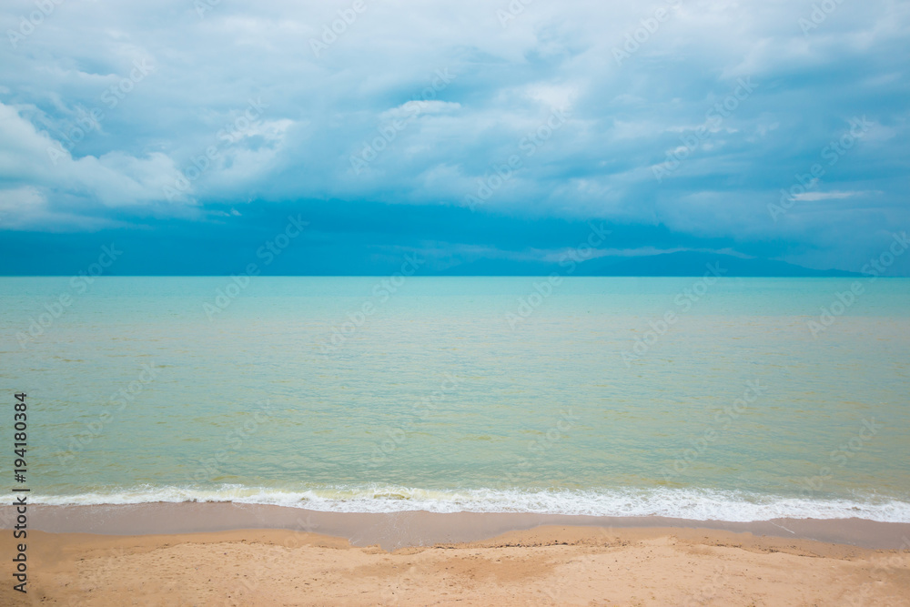 Blue ocean and sand beach under cloudy sky in a bad weather