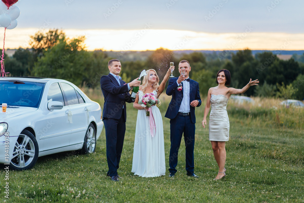 Newlyweds drink champagne with their friends on the field Newlyweds drink champagne with their friends on the field