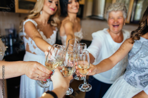 Newlyweds clang glasses with champagne with their family and friends