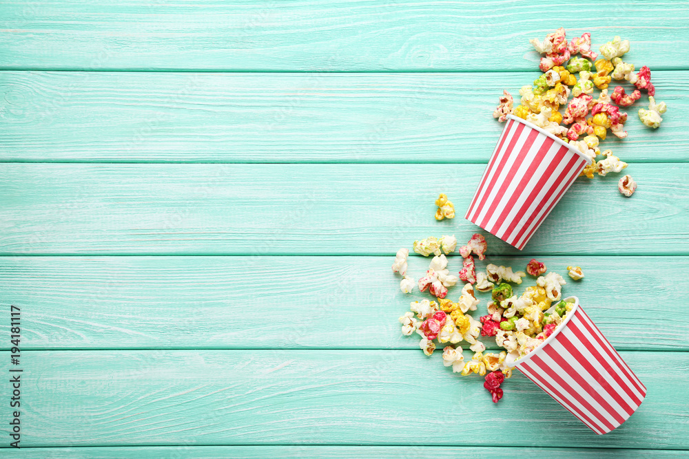 Obraz premium Słodki popcorn w pasiastych filiżankach na miętowym drewnianym stole