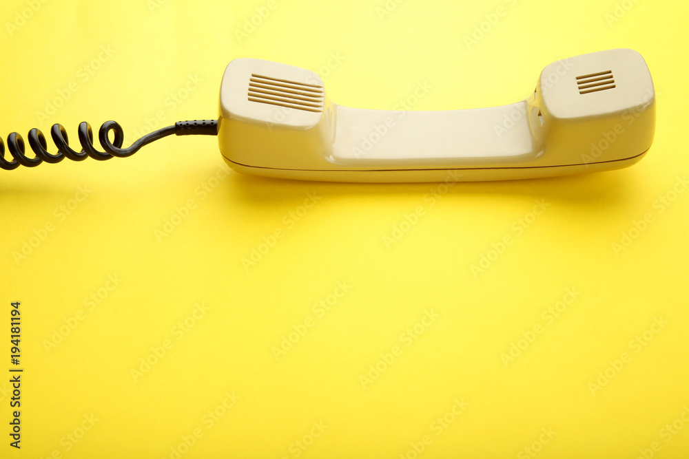 Beige telephone handset on yellow background Beige telephone handset on yellow background