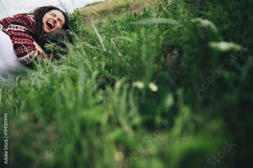 Cheerful bride in wedding dress and sweater on a green lawn