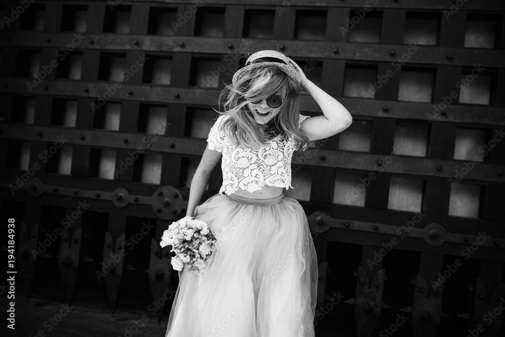 Fototapeta premium The charming bride keeps a bouquet and stands near building