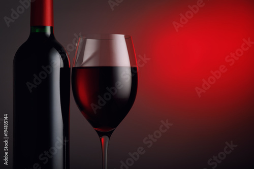  Bottle of red wine with a glass against a dark background and space for text