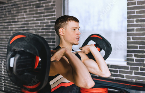 Portrait of sporty muscular fitness man preparing to deadlift a barbell over his head in modern fitness club. Functional training with barbell at the gym. Sport, people and healthy lifestyle concept.