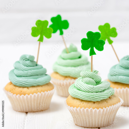 St. Patrick's Day theme colorful horizontal banner. Cupcakes decorated with green buttercream and craft felt decorations in form of shamrock leaves on white background. Copy space. For greeting card photo