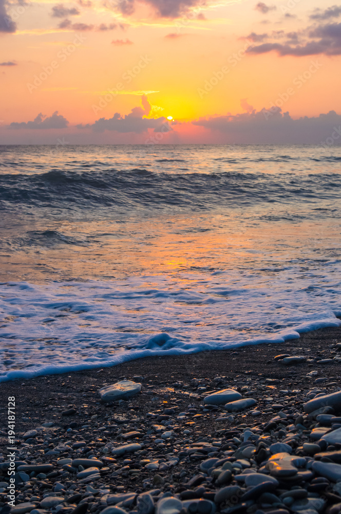 Amazing sea sunset on the pebble beach, the sun, waves, clouds Amazing sea sunset on the pebble beach, the sun, waves, clouds