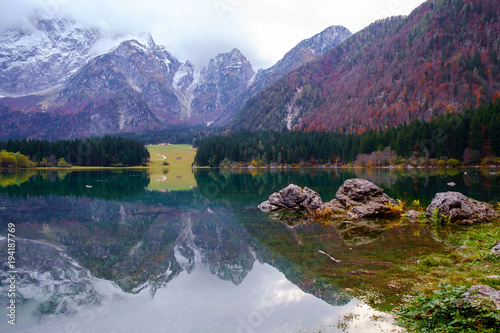 Beautiful Lago di Fusine mountain lake in autumn and Mangart mountain in the background at sunset