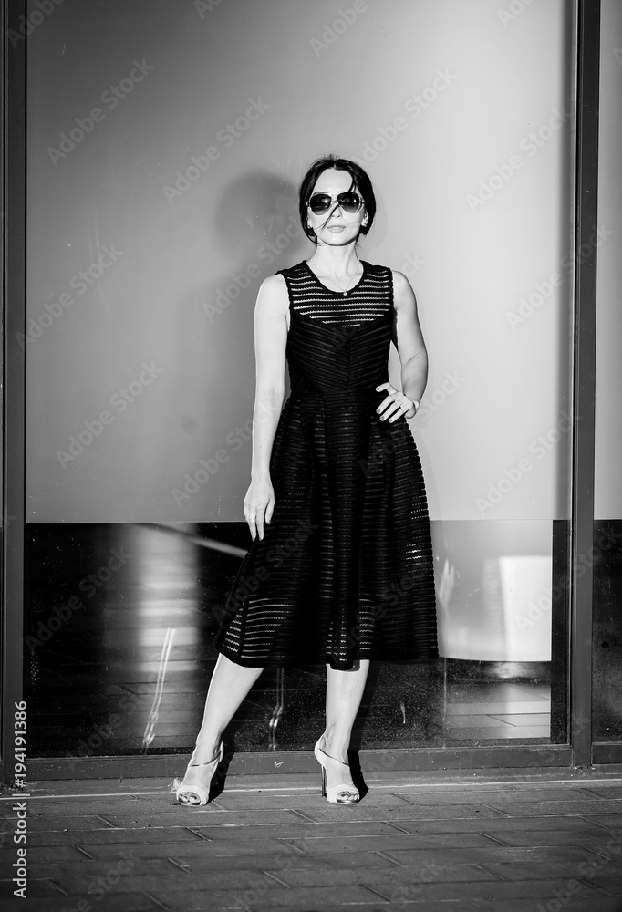 Stylish adult woman in a black dress and sunglasses.