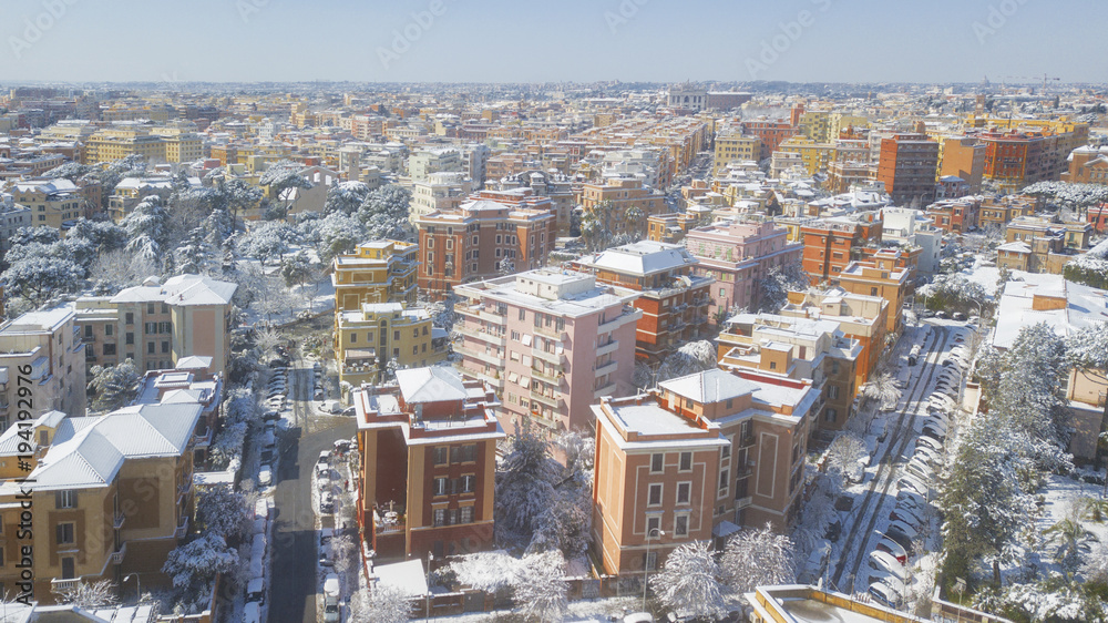 Aerial view of a group of buildings in the Tuscolana district in Rome, Italy. The buildings and streets are unusually covered with snow and ice.The roofs are passable and with antennas and TV dishes.