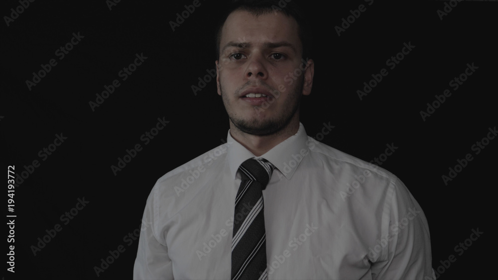 Handsome young businessman in white shirt, black background. Handsome young businessman in white shirt, black background.