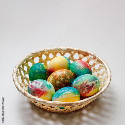 The basket with Easter eggs lies on the table. There is a place for an inscription.