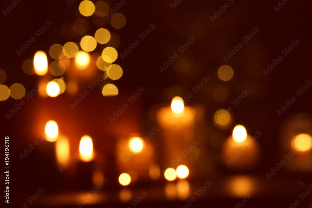 Fototapeta premium Blurred view of beautiful burning candles in darkness