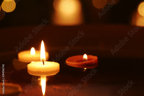 Small burning candles floating in plate with water, closeup