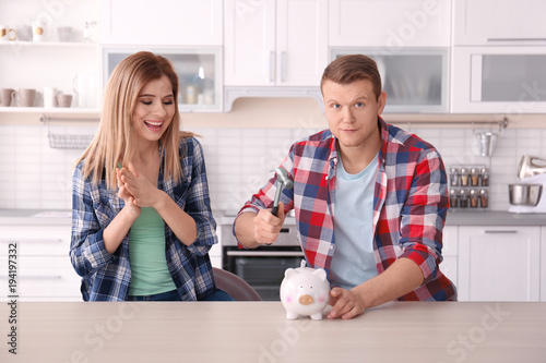 Young couple breaking piggy...