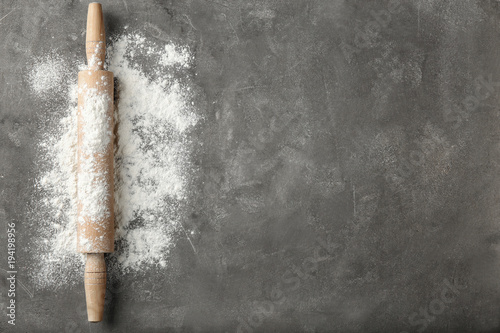 Scattered flour and rolling pin on grey table