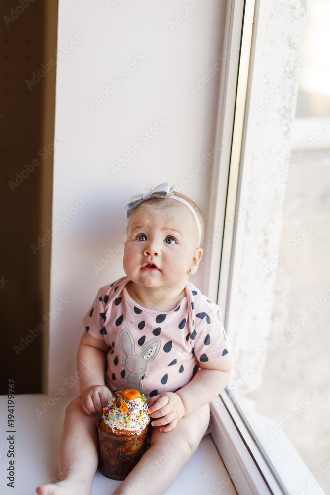 Portrait of cute baby girl with easter cake near the window. Nursing and education for little children Portrait of cute baby girl with easter cake near the window. Nursing and education for little children