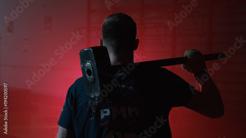Obraz na plátně The concept of rough physical strength when doing dirty male work, a man with a hammer in his hands