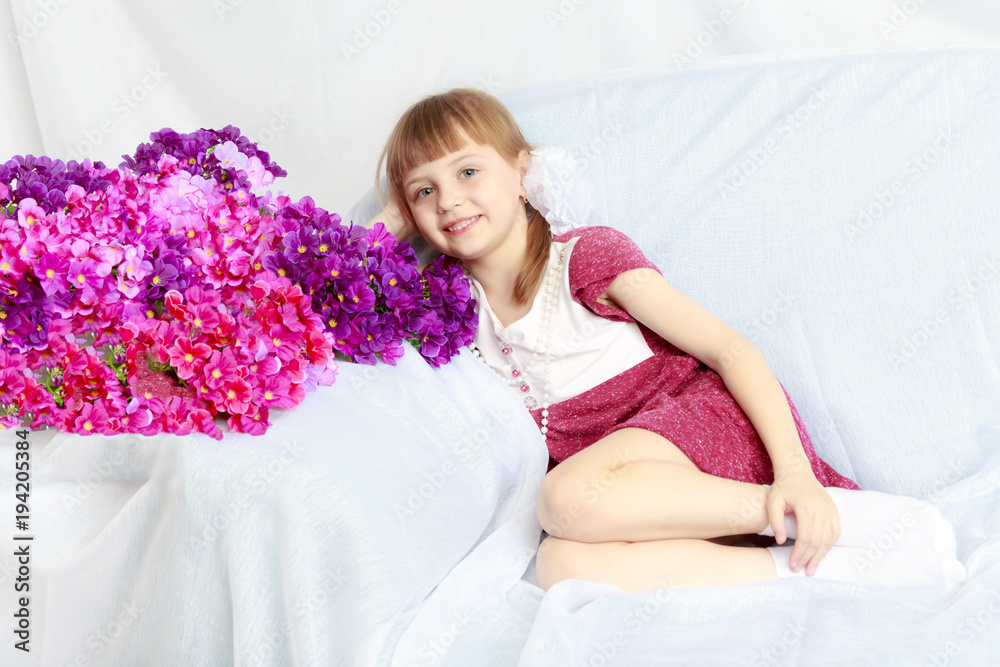 Girl sits next to a bouquet of flowers. Girl sits next to a bouquet of flowers.