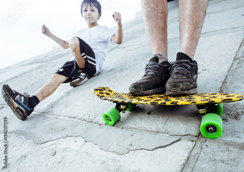 little cute boy with skateboard on playground training with fath photo