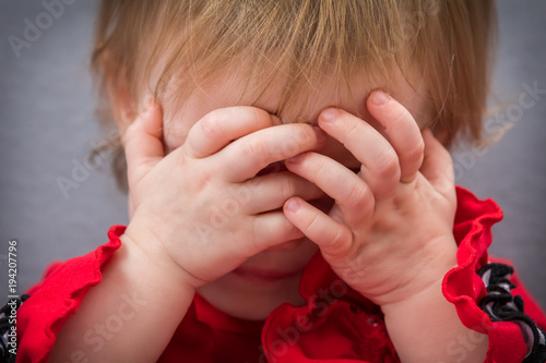 A toddler hiding behind her hands