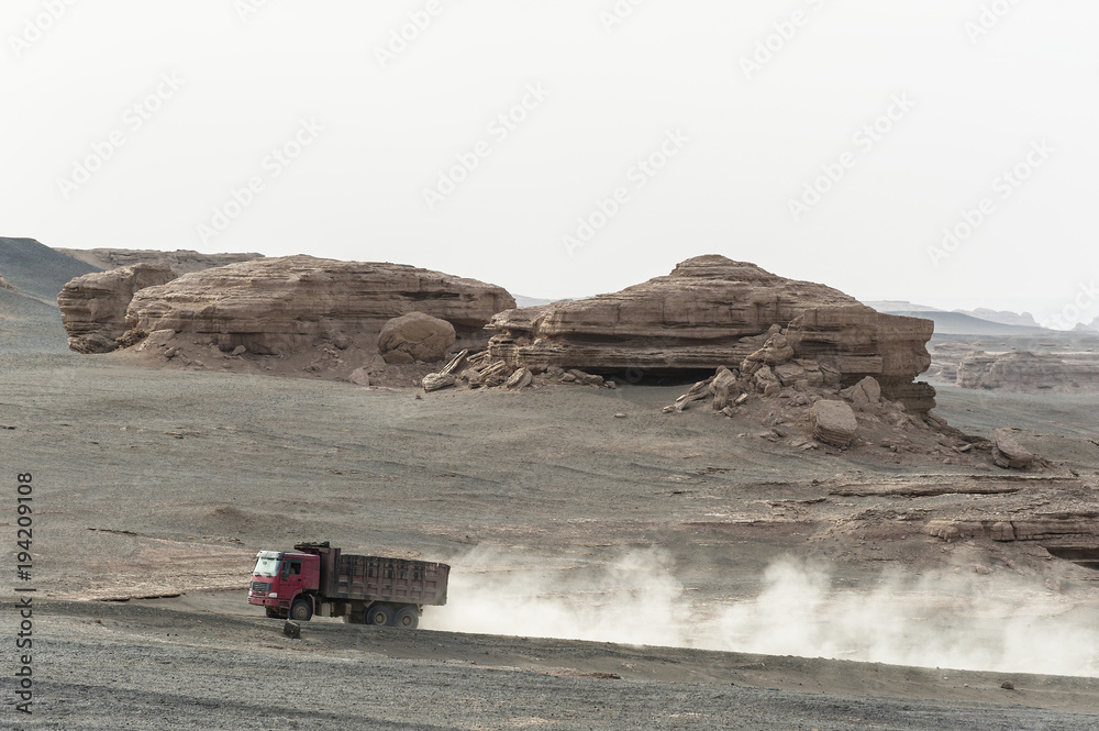 A heavy truck passing Yardang landform in Dunhuang, Gansu of China A heavy truck passing Yardang landform in Dunhuang, Gansu of China