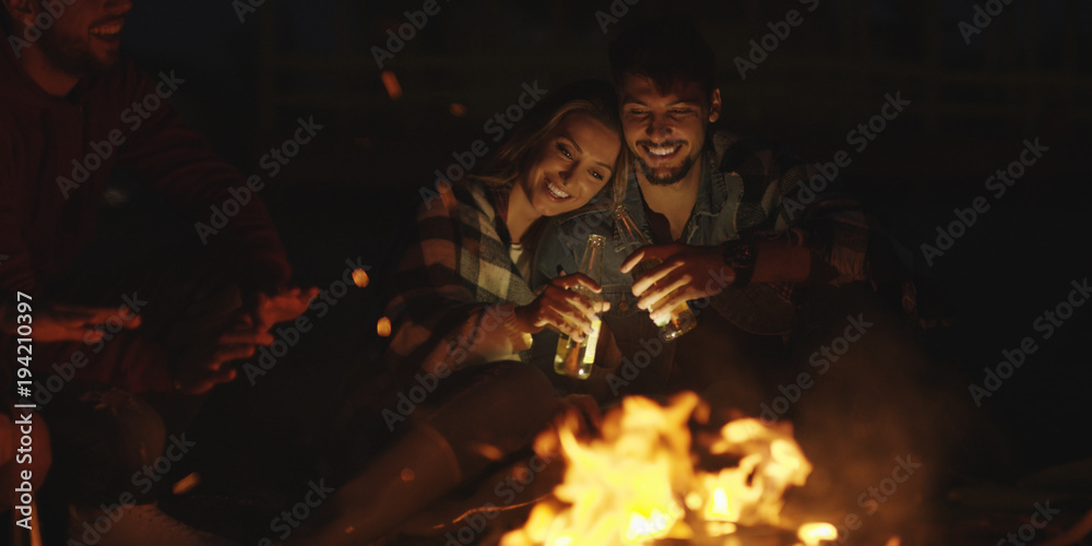 Couple enjoying with friends at night on the beach