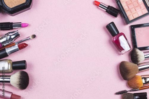 A pink leather make up bag with cosmetic beauty products spilling out on to a pastel background