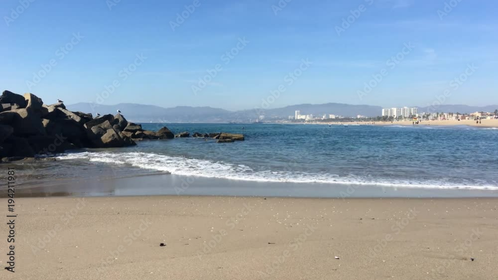 A wide shot of the Venice beach shoreline with rocks on the side of the frame. A wide shot of the Venice beach shoreline with rocks on the side of the frame.