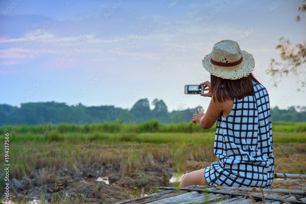 Female woman hands holding phone camera, taking a photo , background sky and Rice field