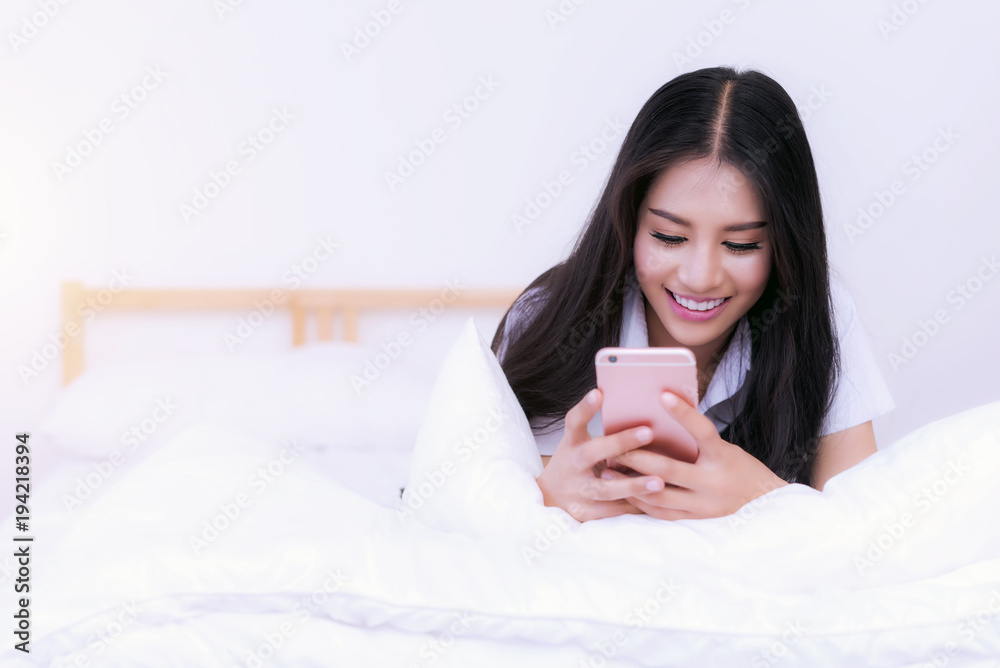 Asian young woman in pajamas playing tablet or smart phone on bed, playing phone after wake up, online shopping at home, news update in morning. Asian young woman in pajamas playing tablet or smart phone on bed, playing phone after wake up, online shopping at home, news update in morning.