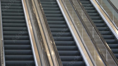 Close up three parallel escalator staircases and handrails moving up and down in an abandoned office building
