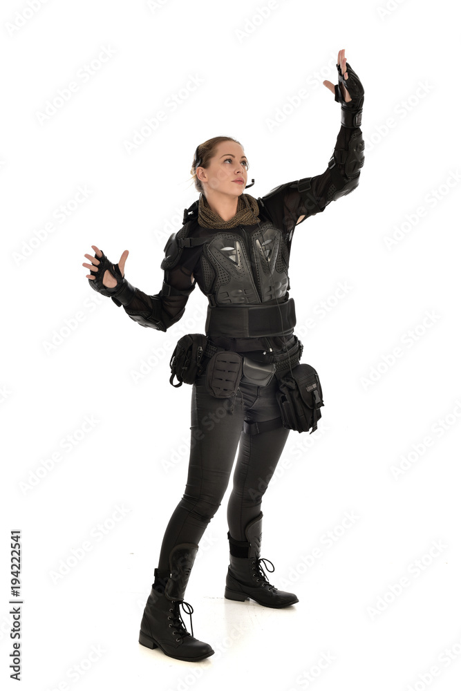 full length portrait of female soldier wearing black tactical armour with arms raised, isolated on white studio background. full length portrait of female soldier wearing black tactical armour with arms raised, isolated on white studio background.