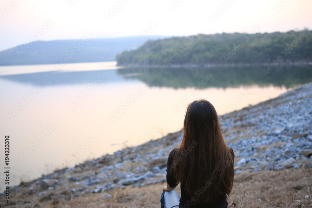 Woman sitting lonely looking at the river.