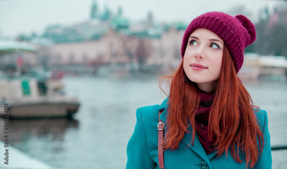 Fototapeta premium Portriat młodej rudowłosej dziewczyny w kapeluszu i płaszczu w Pradze