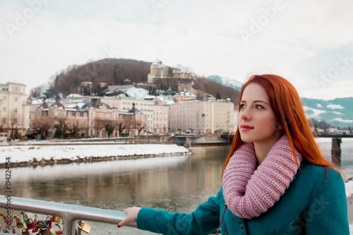 Young redhead girl in coat near lake in Salzburg