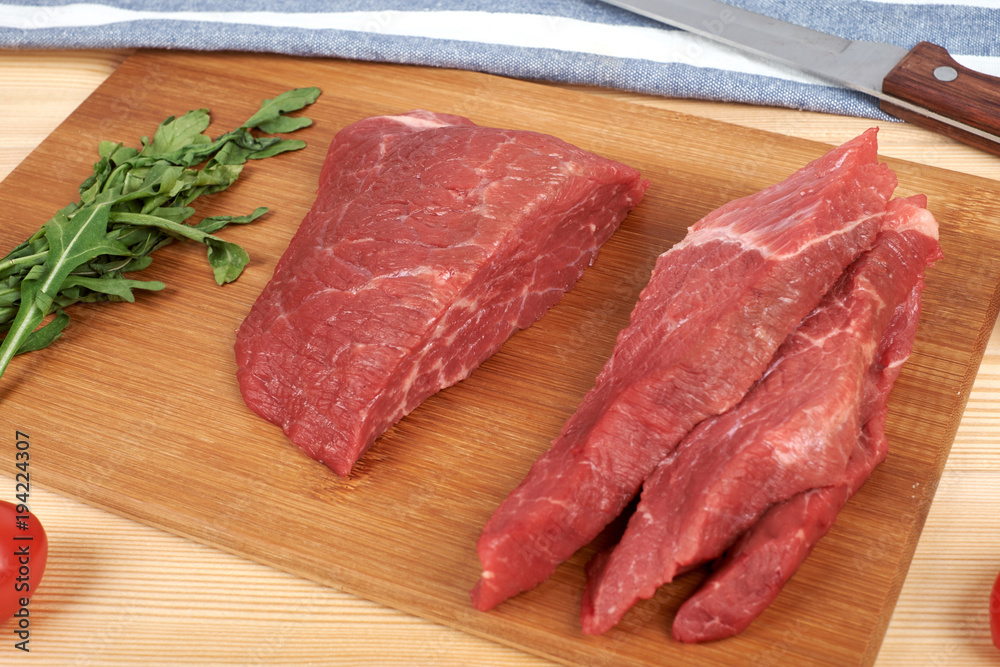 Sliced raw beef on cutting board and vegetables Sliced raw beef on cutting board and vegetables