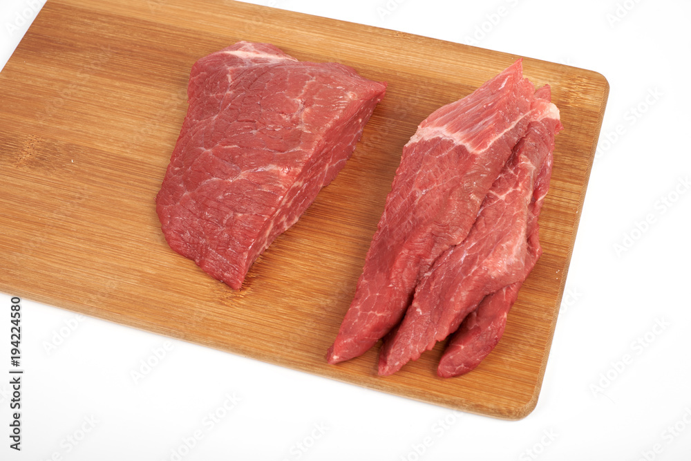 Raw beef piece and slices on wooden cutting board isolated on white background