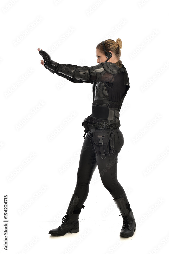 full length portrait of female soldier wearing black tactical armour with arms raised, isolated on white studio background. full length portrait of female soldier wearing black tactical armour with arms raised, isolated on white studio background.