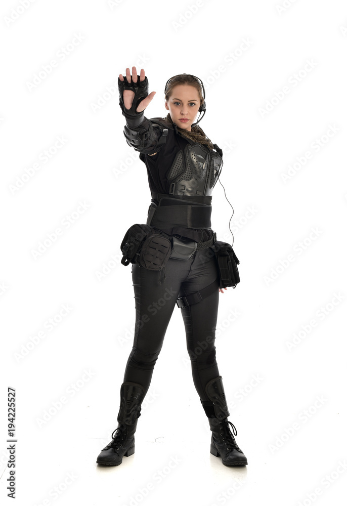 full length portrait of female soldier wearing black tactical armour with arms raised, isolated on white studio background. full length portrait of female soldier wearing black tactical armour with arms raised, isolated on white studio background.