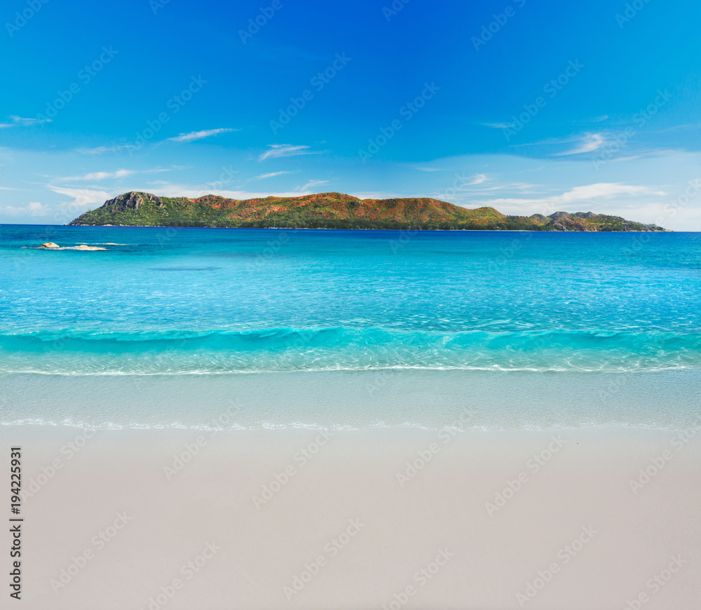 Minimalistic picture. Soft wave of blue ocean on sandy beach with Island in the Background.