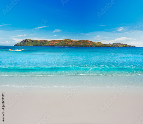 Minimalistic picture. Soft wave of blue ocean on sandy beach with Island in the Background. © Sergei