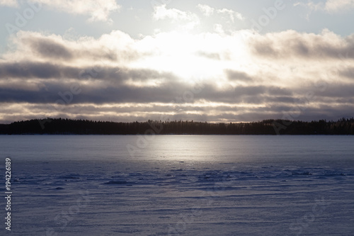 View of the winter lake under the snow and sunset